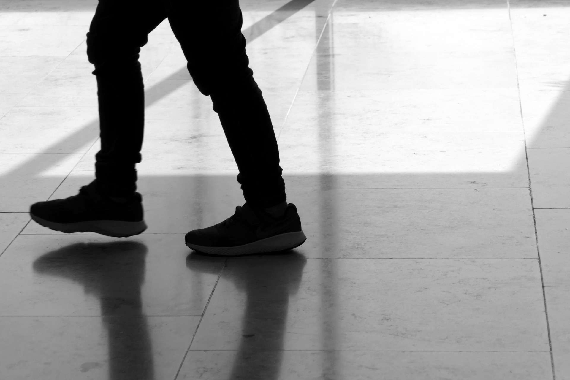 Schwarz-Weiß-Foto gehende Füße auf spiegeldem Boden - aufgenommen 2019 in Neu-Ulm.